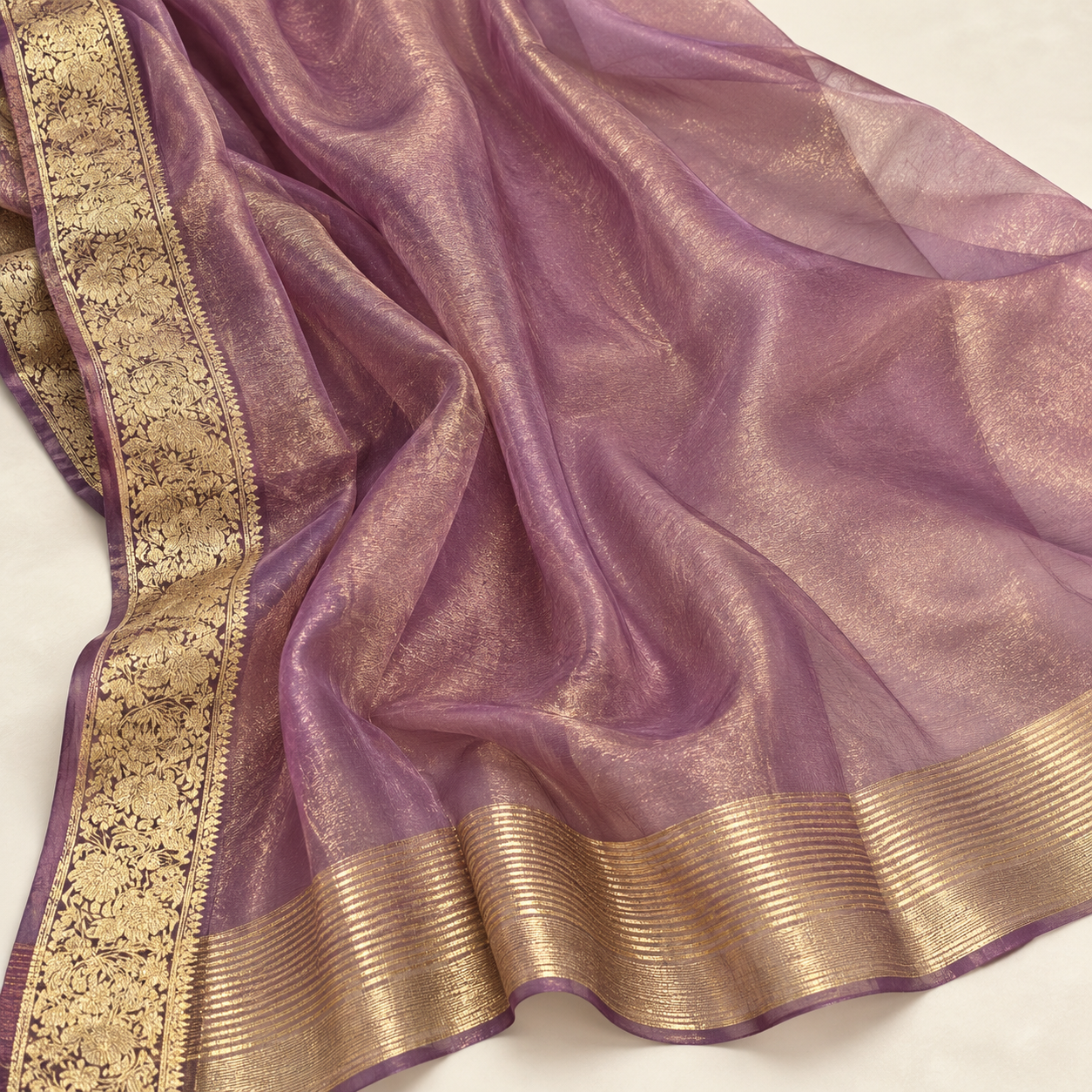 Mauve organza pallu with a gold floral side border and striped metallic end band.