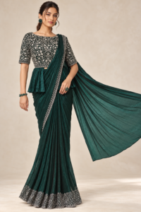 Model wearing an emerald green shimmer chiffon ready-to-wear saree with a silver-detailed border and stitched handwork blouse.